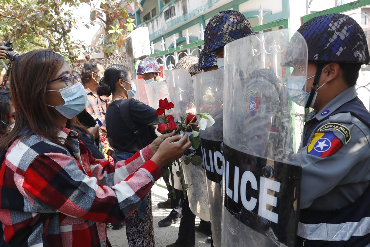 Supporters give roses to police while four arrested activists make a court appearance in Mandalay, Myanmar, Friday, Feb. 5, 2021. Hundreds of students and teachers have taken to Myanmar