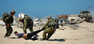 
Israeli soldiers scuffle with a Jewish settler trying to prevent army bulldozers from demolishing uninhabited former Egyptian resort homes outside the Jewish settlement of Shirat Hayam in the southern Gaza Strip on Sunday. 
 (Associated Press / The Spokesman-Review)