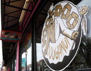 The corporate logo adorns one of the windows of the storefront of Voodoo Doughnuts on East Colfax Avenue in Denver on Tuesday, April 4, 2017. A man trying to eat a half-pound glazed doughnut in 80 seconds as part of the shop's eating challenge choked to death Sunday at the business. (AP Photo/Thomas Peipert)