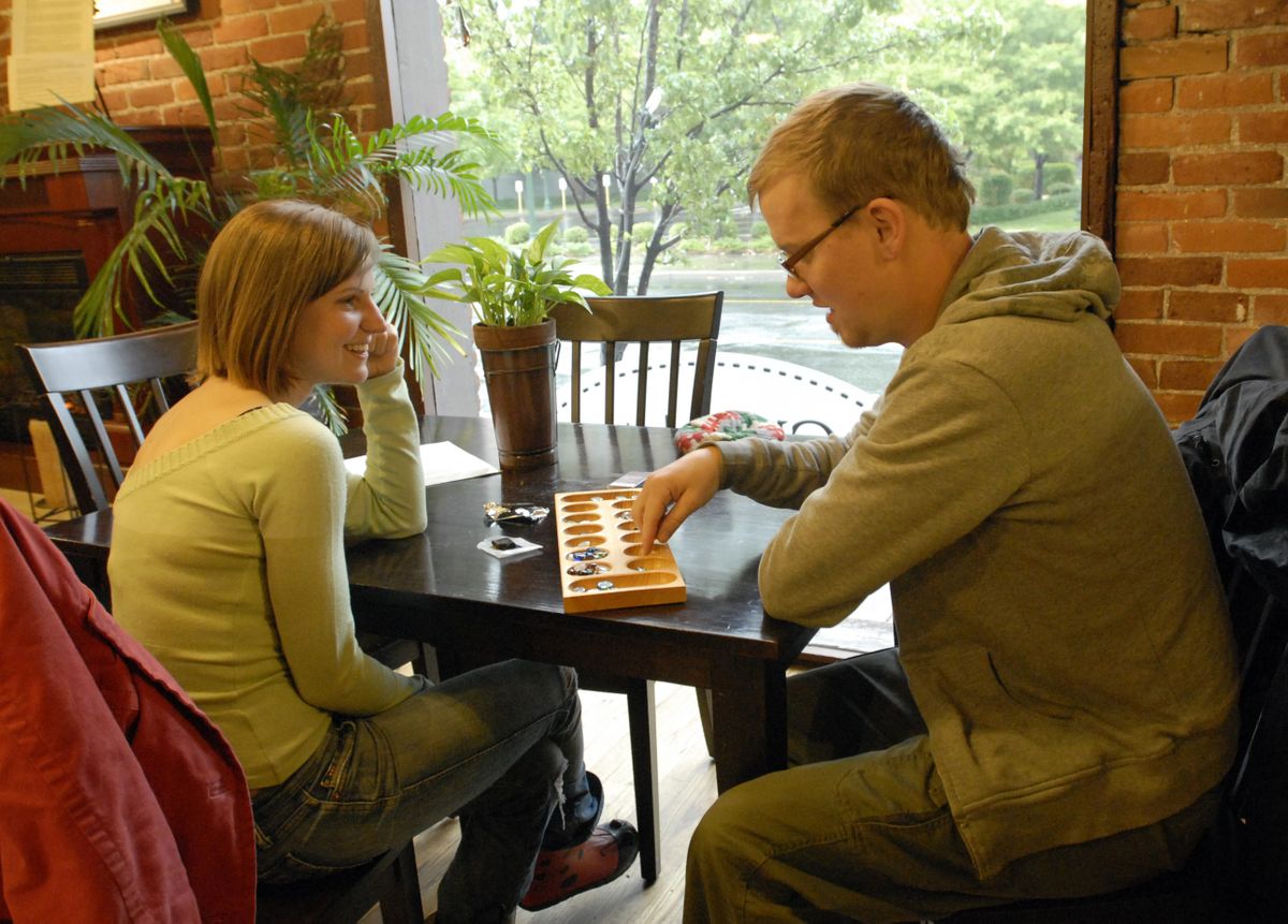 Melanie Kelly and Aaron Swinkels, of Spokane, went “out for a walk in the rain” Sunday and stopped at Chocolate Apothecary at the Flour Mill to have some chocolate and dry out over a game of mancala. “We’re going puddle jumping on the way back,” Swinkels said.  (J. BART RAYNIAK / The Spokesman-Review)
