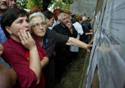 Ossetians read lists of those hostages who escaped outside Beslan's hospital, North Ossetia, on Saturday.
(Associated Press / The Spokesman-Review)