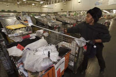 
Lucretia Thomas pulls sorted parcels at a U.S. Postal Service processing and distribution center in Los Angeles last month. The Postal Service and its counterparts in other countries are expanding into electronic services. Associated Press photos
 (Associated Press photos / The Spokesman-Review)