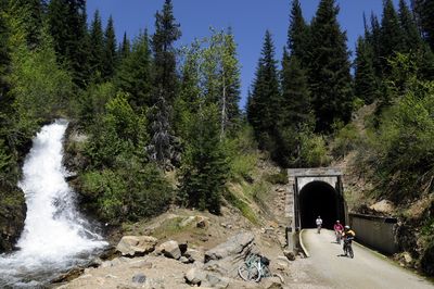 Bicyclists exit the Taft Tunnel and emerge into the surrounding beauty of the national forest. The Taft Tunnel is the longest of several railroad tunnels along the Route of the Hiawatha, a trail that follows the path of the long-gone railroad through the region on the Montana-Idaho border.  (File / The Spokesman-Review)