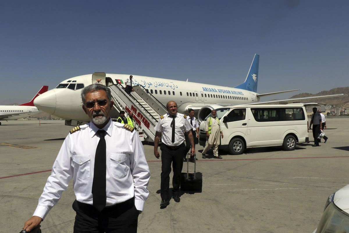 Pilots of Ariana Afghan Airlines walk on the tarmac after landing at Hamid Karzai International Airport in Kabul, Afghanistan, Sunday, Sept. 5, 2021. Some domestic flights have resumed at Kabul