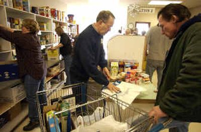 
Volunteer Terry Sparrow, left, helps Tim Eagleburger, right, with his order at the Valley Food Bank on Wednesday. The Valley Community Center wants the food bank to merge with its organization. 
 (Liz-Anne Kishimoto / The Spokesman-Review)