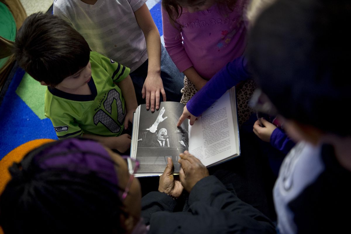 Teacher Talibah Adeeba’s students point excitedly to a photo of Martin Luther King Jr. as Adeeba reads to them Friday at the Martin Luther King Jr. Family Outreach Center in Spokane. (Tyler Tjomsland / The Spokesman-Review)