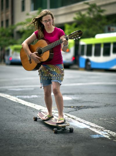 Multitasking: “I'm just riding and learning,” says Sky Belieu as she practices her guitar while skatebording through downtown Spokane on Monday. (Colin Mulvany)