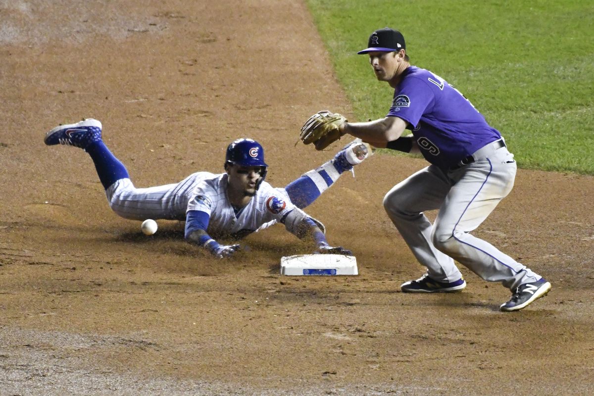 Chicago Cubs’ Javier Baez, left, slides into second base safely on an RBI double as Colorado Rockies second baseman DJ LeMahieu  makes a late tag during the eighth inning  Tuesday in Chicago. (David Banks / AP)