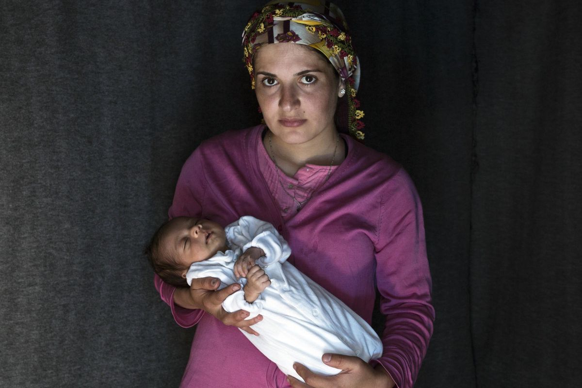 In this photo taken on Friday, May 13, 2016, 23-year-old Rojin, a Kurdish-Syrian mother from the city of Qamishli, Syria, poses with her baby girl Beritan in a tent made of blankets given by the UNCHR at the refugee camp of the northern Greek border point of Idomeni. Beritan, the family’s first child, was born on Sunday, April 10, 2016, in the hospital of the nearby town of Kilkis. The three-member family wants to go to Switzerland. (Petros Giannakouris / AP)