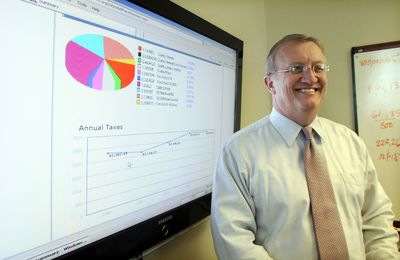 Ralph Baker, Spokane County assessor, stands in his office Tuesday  with the screen he uses to display assessment records during meetings.  (Jesse Tinsley / The Spokesman-Review)