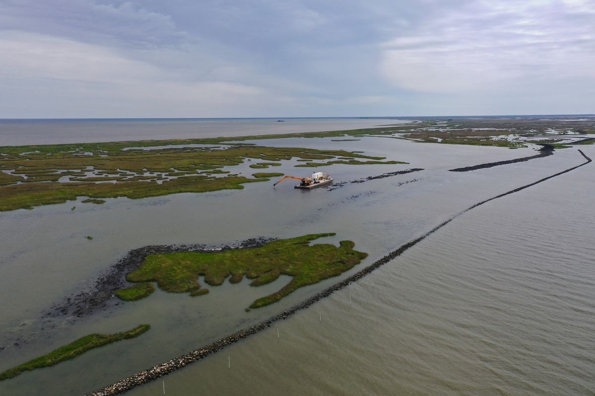 Machinery can be seen on a barge working on the Lake Borgne Marsh Creation Project in Yscloskey, La., in March 2023. Containment dikes are being built with dredged sediment that will protect existing marshland from further erosion. (Ricky Carioti/The Washington Post)