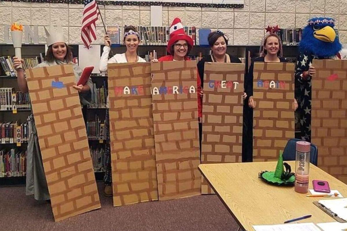 A group of Middleton teachers dressed in patriotic attire stand behind a fake wall with the words “Make America Great Again.” (Courtesy Idaho Press)