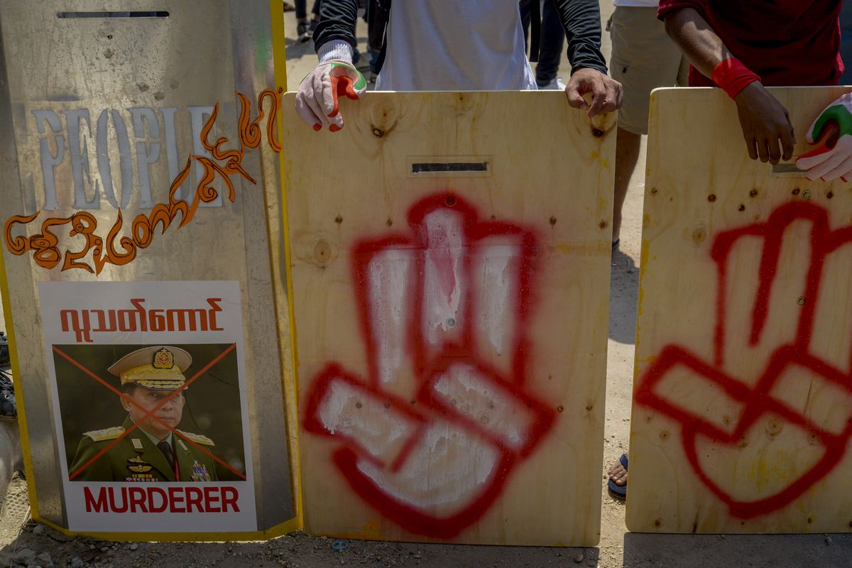 Anti-coup protesters stand behind a line of makeshift shields marked with three-fingered salute and defaced image of Commander in chief, Senior Gen. Min Aung Hlaing as they gather to protest in Yangon, Myanmar Tuesday, March 9, 2021. Demonstrators in Myanmar