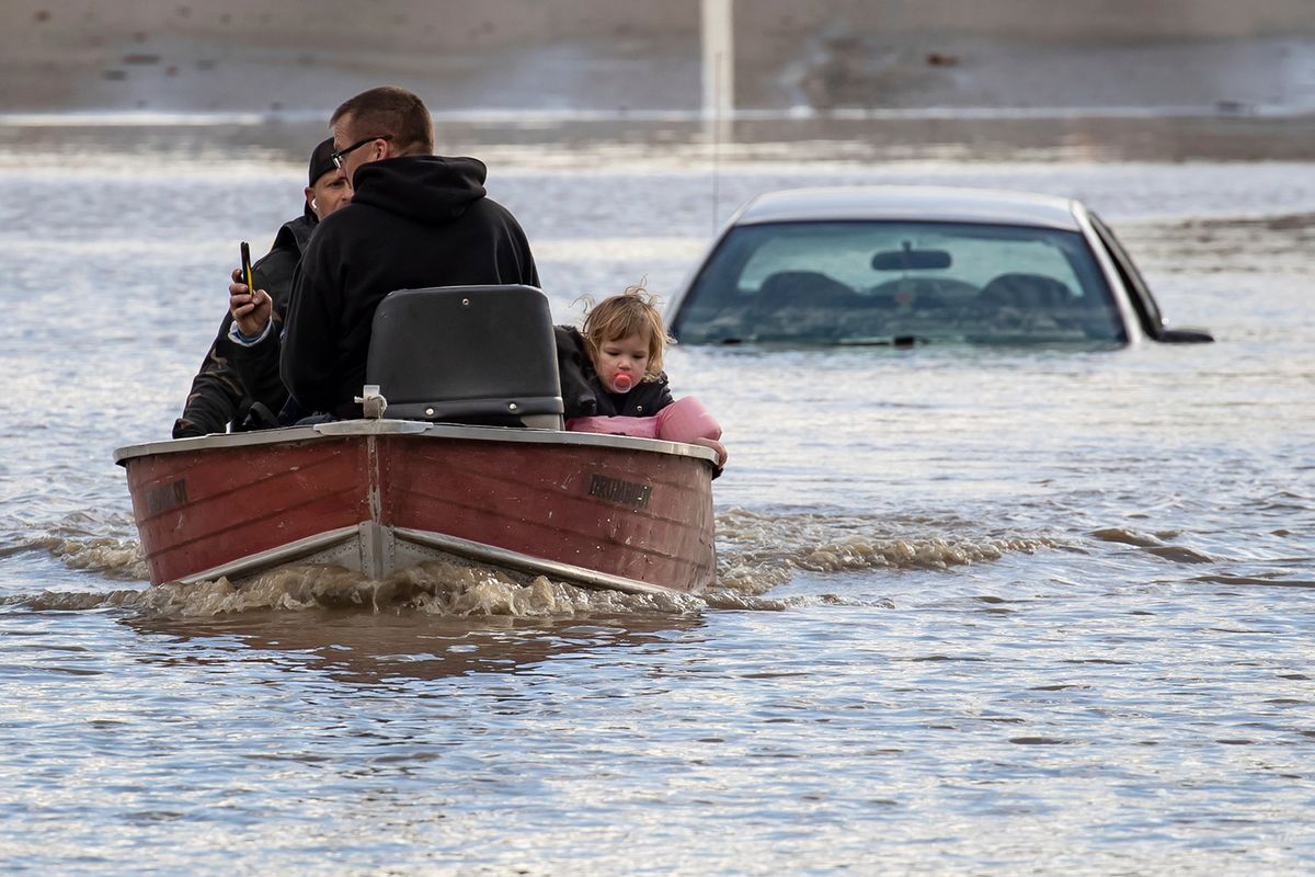 People, including a toddler and dog who were stranded by high water due to flooding are rescued by a volunteer operating a boat in Abbotsford, British Columbia, on Tuesday, Nov. 16, 2021.  (Darryl Dyck)