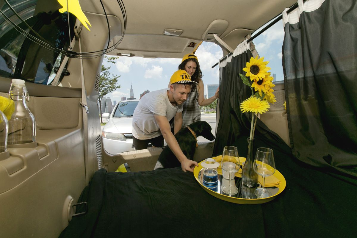 Airbnb renters Mike and Tabitha Akins and their dog Bagheera check their accommodations in a decommissioned 2002 Honda Odyssey yellow taxi, in the Queens borough of New York. Their view includes the Empire State Building, background left. (Associated Press)