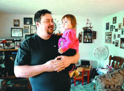 
Brent Bruns, of Rathdrum, holding his daughter, Florence, has been hobbled by a heart ailment that leaves him gasping for breath after a few minutes of walking.  The former scuba diver, who weighs more than  350 pounds, is awaiting gastric bypass surgery. 
 (JESSE TINSLEY i / The Spokesman-Review)
