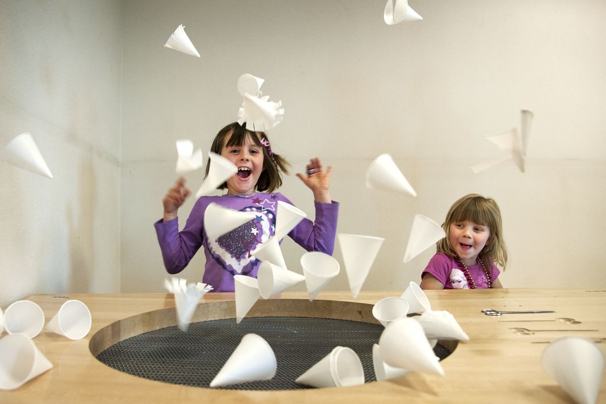 Karolina Flanagan, 6, and her sister, Nora, 4, watch paper cups fly into the air after being launched by a fan at the Airheads display Wednesday during the opening of the Mobius Science Center in the Spokane Public Library in downtown Spokane. (Dan Pelle)