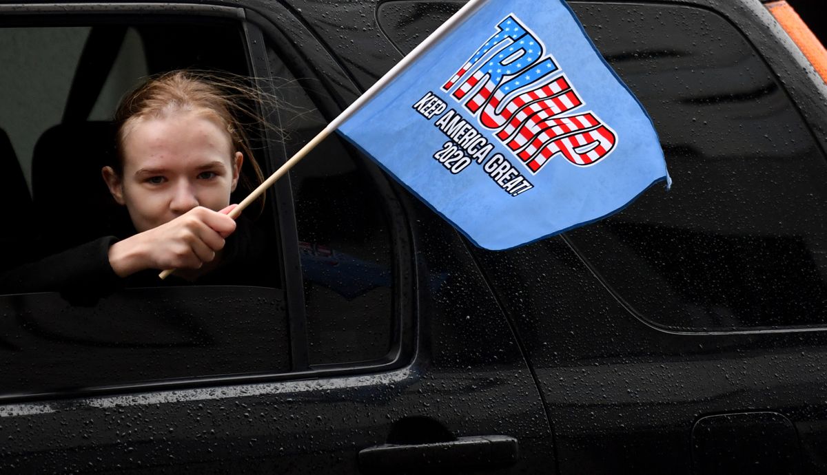 Desi Lloyd, waves a Trump flag out the window of her father Roy’s car as they pass the Spokane Convention Center during a “Stop the Steal” rally on Wednesday.  (Tyler Tjomsland/THE SPOKESMAN-REVIEW)