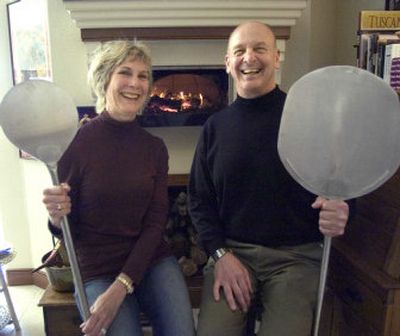 
Bruce and Carol Becker sit in front of the wood-fired oven they had installed in their kitchen when they built their house six years ago. Each of them holds a peel used to handle food in the oven. 
 (The Spokesman-Review)