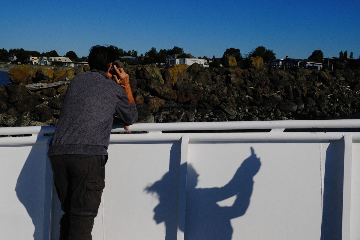 Gradyn Comfort, 62, of Houston, talks on his cellphone as his wife, who asked to remain unidentified, snaps a photo on the Salish Express arriving at the Point Roberts Marina on Thursday.  (Tyler Tjomsland/The Spokesman-Review)