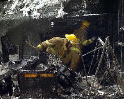 Firefighters mop up a house fire in the West 900 block of Alice Avenue on Monday. Investigators think it was started by a heating pad.
(Colin Mulvany / The Spokesman-Review)