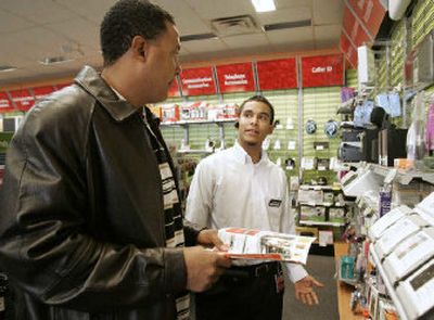 
RadioShack sales associate Carlos Penate, right, assists customer Darryl Johnson, left, of Coppell, Texas, at a RadioShack store in Carrollton, Texas. When an assistant manager found out that Penate was looking for some extra holiday cash, it was suggested he go from shopper to sales associate. Two weeks later, Penate was hired. 
 (Associated Press / The Spokesman-Review)