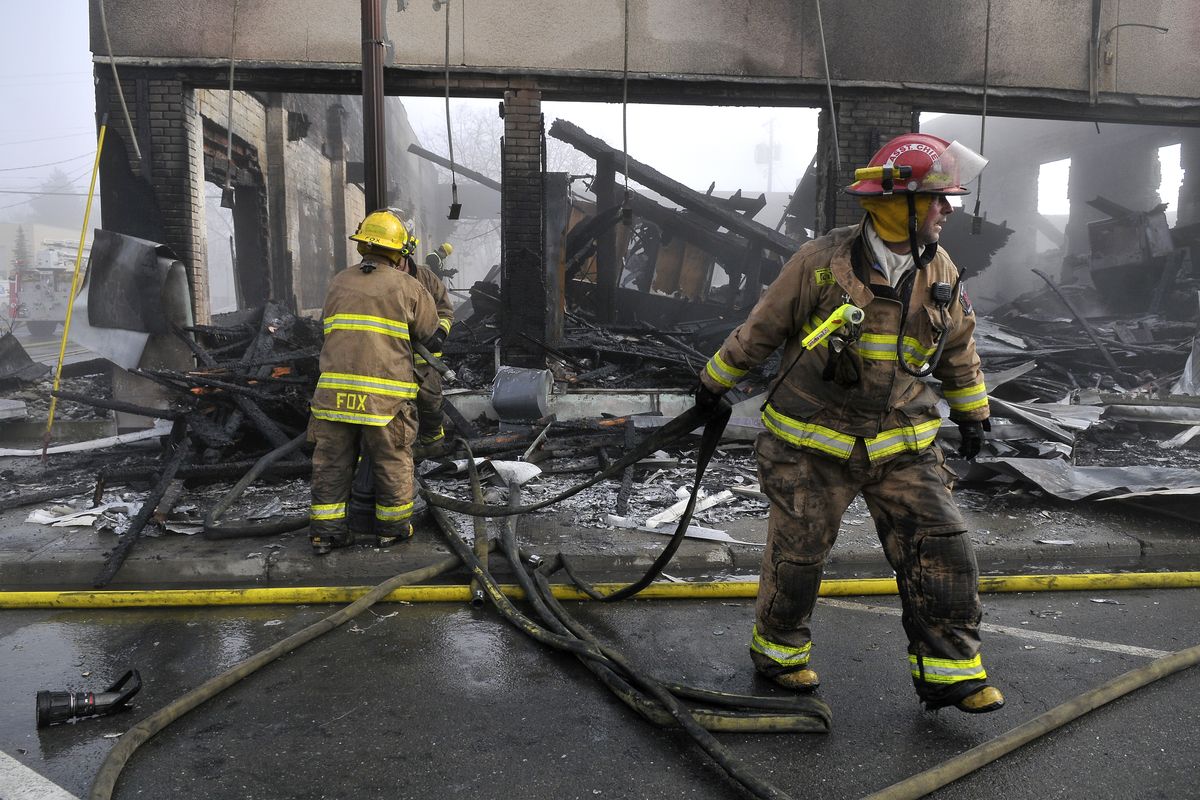Colville Fire Department firefighters pull their hoses from the shell of Saundra’s Furniture and Design on Sunday. The fire started around 8 p.m. Saturday night, engulfing the whole building. (Jesse Tinsley)