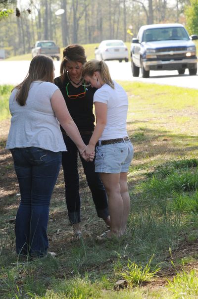 Jordan Crowe, Raegan Fulmer and Natalie White, from left, pray Friday near the spot where Aaron Hill died in a crash. (Associated Press)
