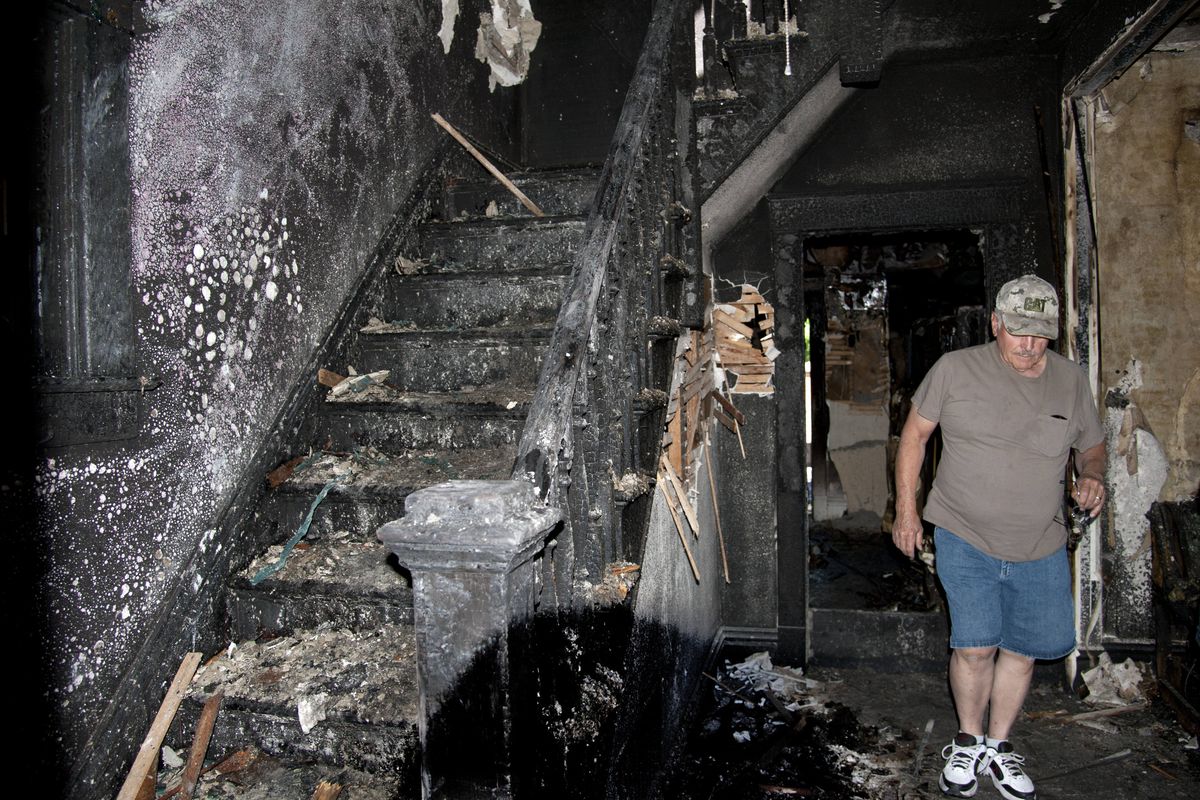 Darrel Jepsen inspects the damage to his son Jack’s northeast Spokane home Tuesday following the second fire in the structure this month. (Dan Pelle)