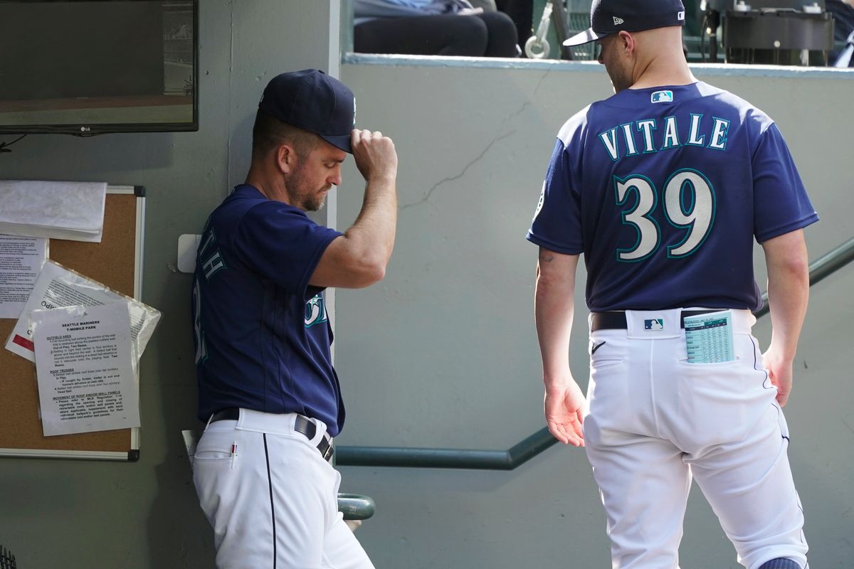Seattle Mariners pitching coach Pete Woodworth, left, and major league field coordinator Carson Vitale (39) linger in the dugout after the team