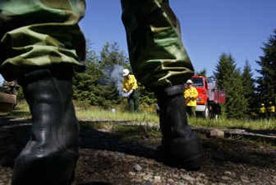 
Larry Scott, center, lights a flare as he teaches Washington Army and Air National Guard members how to fight and control wildfires last week at Fort Lewis, Wash. 
 (Associated Press / The Spokesman-Review)