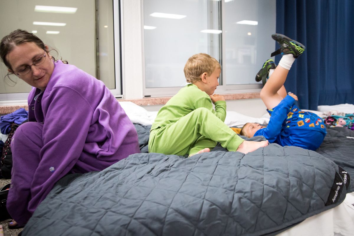 Becca McKnight sits down on her bed for the night while 4-year-old Avery Rich, center, and 8-year-old Orion Rich exhaust the last of their energy while the evening winds down before lights out in the Family Promise of Spokane shelter on Aug. 11. (Libby Kamrowski/The Spokesman-Review)