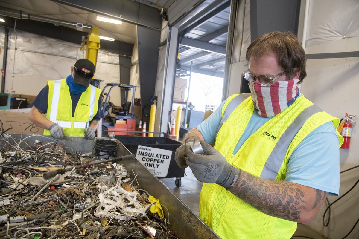 Malachi Chaney, right, tests a piece of copper wire with a magnet to make sure it’s not iron before dropping it into a bin for recycling Sept. 9. At left is his co-worker Scott Strickland. Both of them work at the Investment Recovery Center at Avista Utilities where they sort cast-off wiring and equipment for recycling, an effort that hires nine adults with intellectual and developmental disabilities. The Arc of Spokane provided the workers; the partnership is 30 years old.  (Jesse Tinsley/The Spokesman-Review)