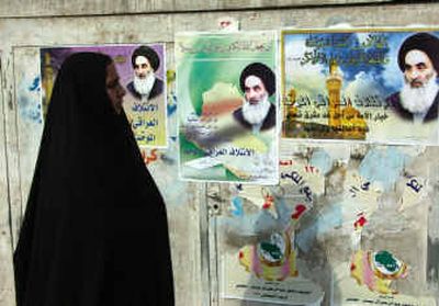 
An Iraqi woman walks Friday past posters advertising next month's landmark elections in Baghdad.
 (Associated Press / The Spokesman-Review)