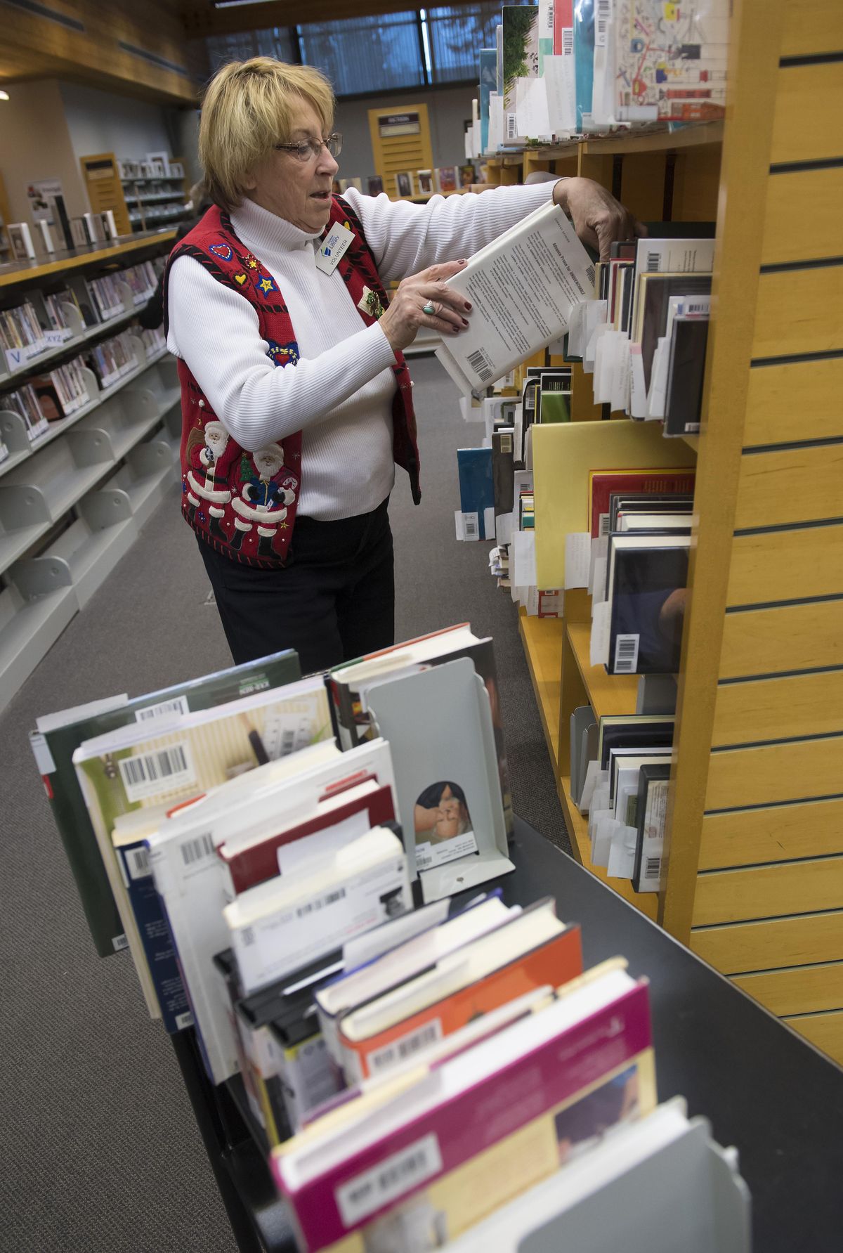 Anne Sanders, a volunteer at Spokane Public Library’s South Hill branch, shelves books on reserve for people, Friday, Dec 22, 2017. (Colin Mulvany / The Spokesman-Review)