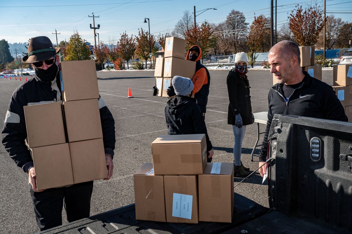 Volunteers Joel Adrian and Tony Skinner of Sysco Spokane load restaurant owner Tim Suor’s pickup with donated food boxes on Tuesday in the Avista Stadium parking lot for Suor’s employees who continue to face challenges during the COVID-19 pandemic.  (Colin Mulvany/The Spokesman-Review)