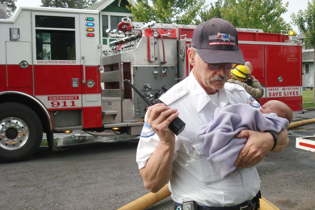  American Medical Response paramedic John Elser holds 2-week-old Summerlyn Cope, whose mother, Sara Farrell, rescued her from their burning home on West Kiernan Avenue Thursday morning. Farrell’s hair was singed, but she and her daughter weren’t injured.  (John  Craig)