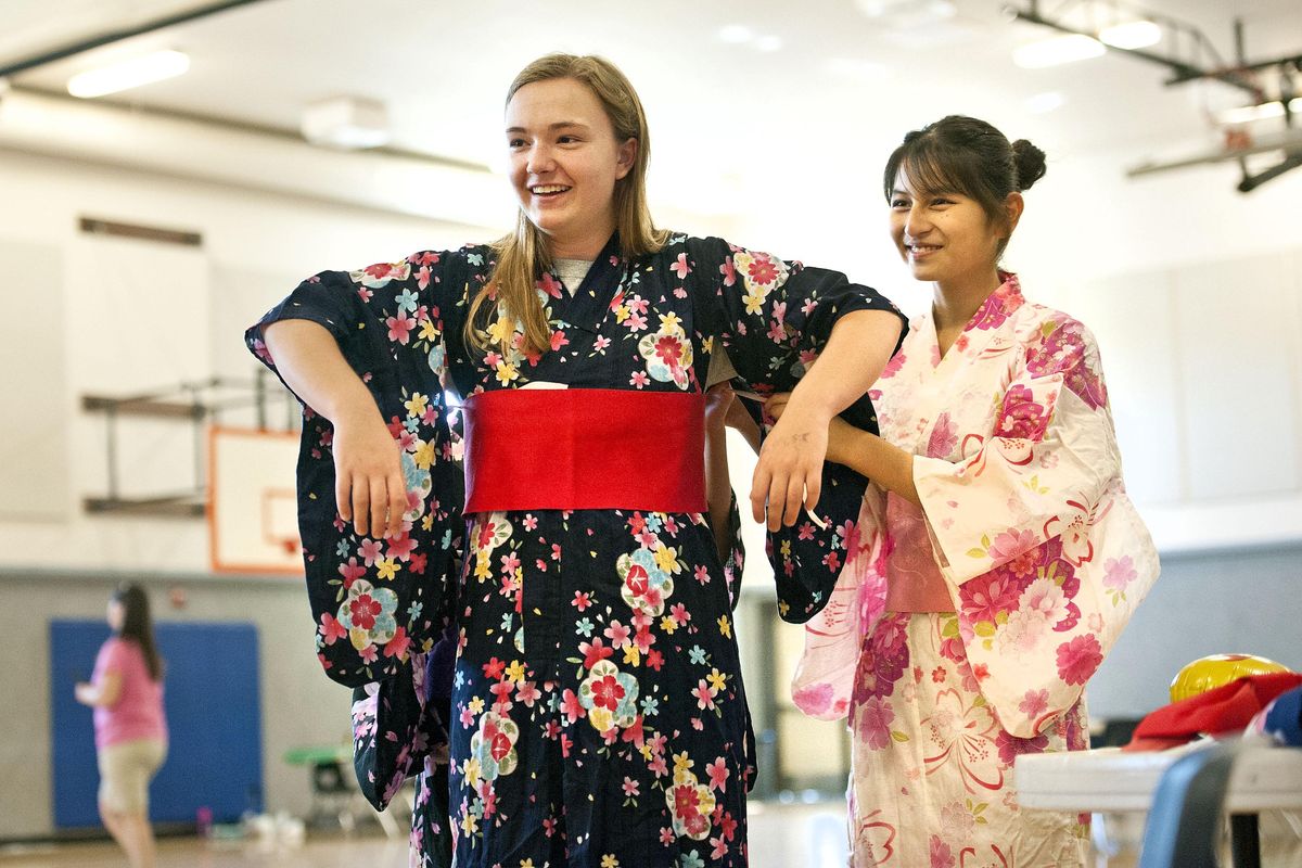 Mattie Craner, 14, smiles as Compass USA exchange student Asumi Takizawa,15, helps her try on a traditional Japanese kimono during the cultural fair at Spokane Valley Nazarene Church on Thursday, July 27, 2017. (Kathy Plonka / The Spokesman-Review)