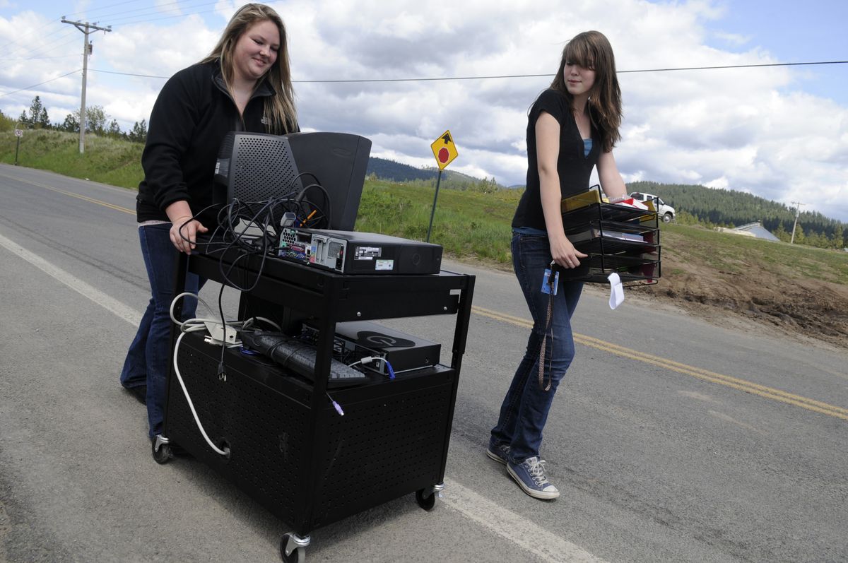 Freeman High  sophomore Morgan Romey, left, and junior Rochelle Wakker move equipment down South Jackson Rd. from the high school to a group of portable buildings on Friday.  (Jesse Tinsley / The Spokesman-Review)