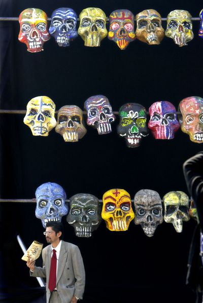 In this 2006 file photo, a man stands in front of an art piece of painted skulls in Mexico City’s Zocalo plaza during Day of the Dead festivities. Day of the Dead, a colorfully macabre celebration harkening back to the Aztecs, is observed on the Catholic All Saints’ Day. “El Dia de Los Muertos” is when families take picnics to the cemeteries to decorate the graves of departed relatives with marigolds, candles and sugar skulls. (Associated Press)