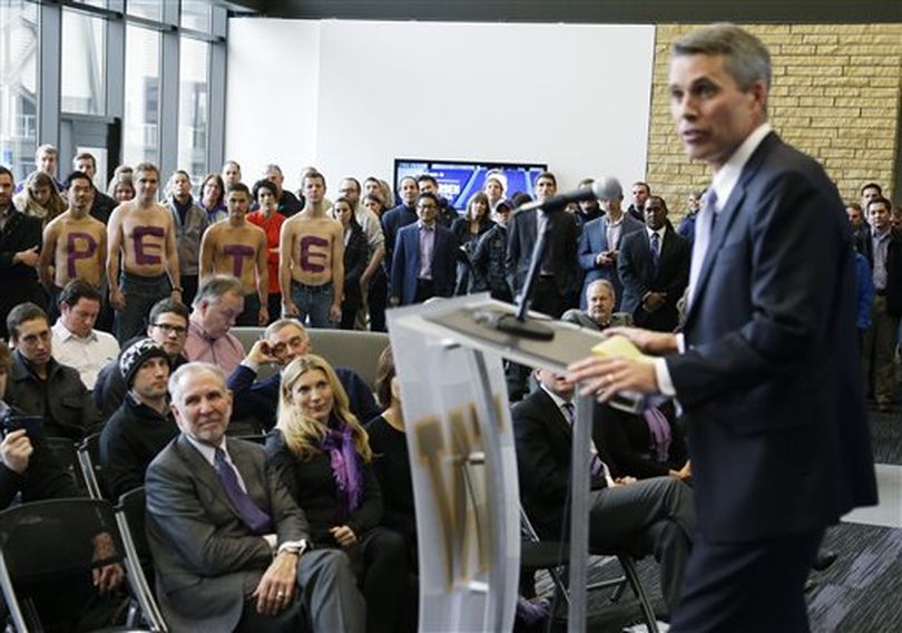 Shirtless fans spell out P-E-T-E at left, as Chris Petersen, right, takes questions from reporters after being introduced as the new head football coach at the University of Washington, Monday, Dec. 9, 2013, in Seattle. Petersen formerly was head coach at Boise State. (AP / Ted S. Warren)