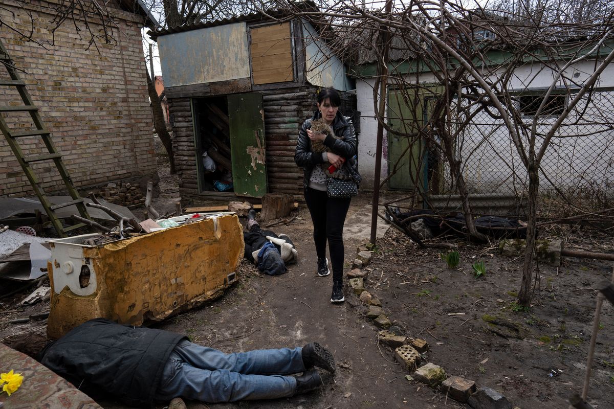 FILE - Ira Gavriluk holds her cat as she walks next to the corpses of her husband and her brother, who were killed in Bucha, on the outskirts of Kyiv, Ukraine, Monday, April 4, 2022.  (Rodrigo Abd)