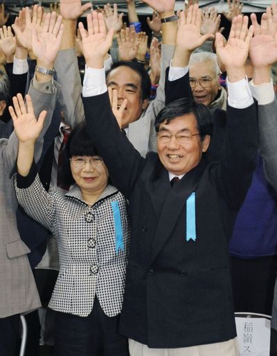 Anti-U.S. base candidate Susumu Inamine celebrates with his wife, Ritsuko, and supporters.  (Associated Press / Kyodo News)