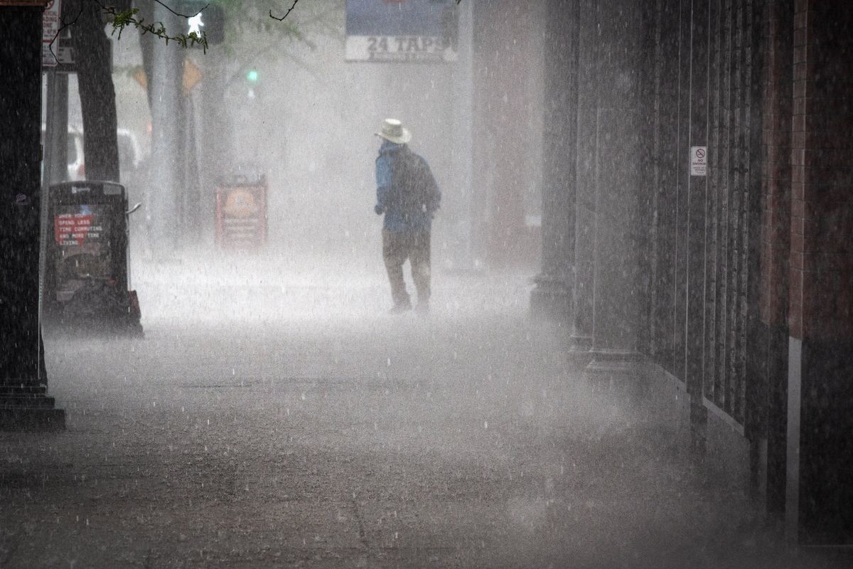 During a torrential downpour, a pedestrian makes his way around the flooded intersection of Lincoln Street and Riverside Avenue on May 16, 2019, in downtown Spokane.  (COLIN MULVANY/THE SPOKESMAN-REVIEW)