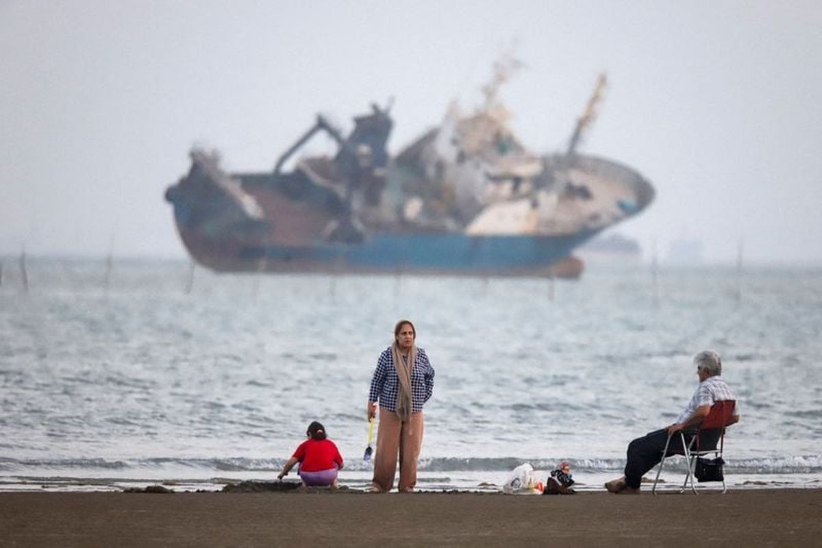 People gather on a beach, as a vessel in the Strait of Hormuz is visible on May 31, near the beach of Bandar Abbas, Iran.  (Reuters )