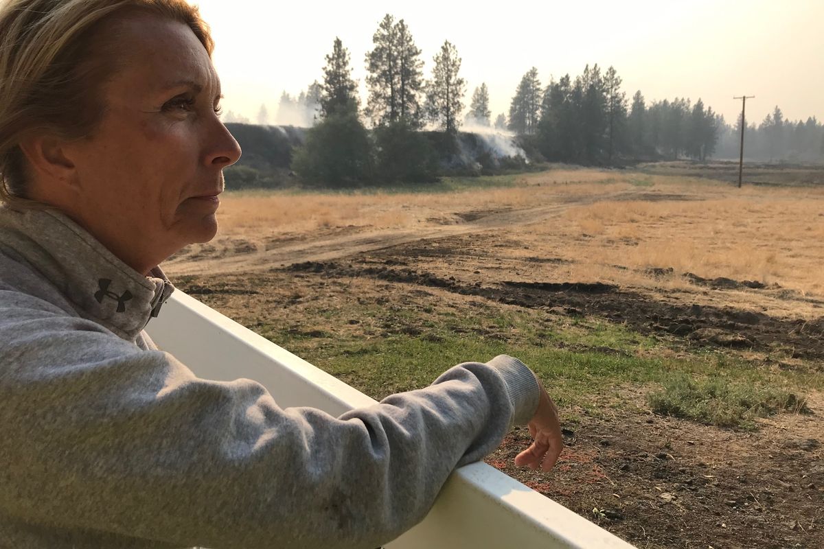 Traci Cole looks out at her ranch Tuesday as the Whitney Road Fire continues to burn. The fire surrounded her home 10 miles west of Davenport, but it was saved by firefighters.  (THOMAS CLOUSE/The Spokesman-Review)
