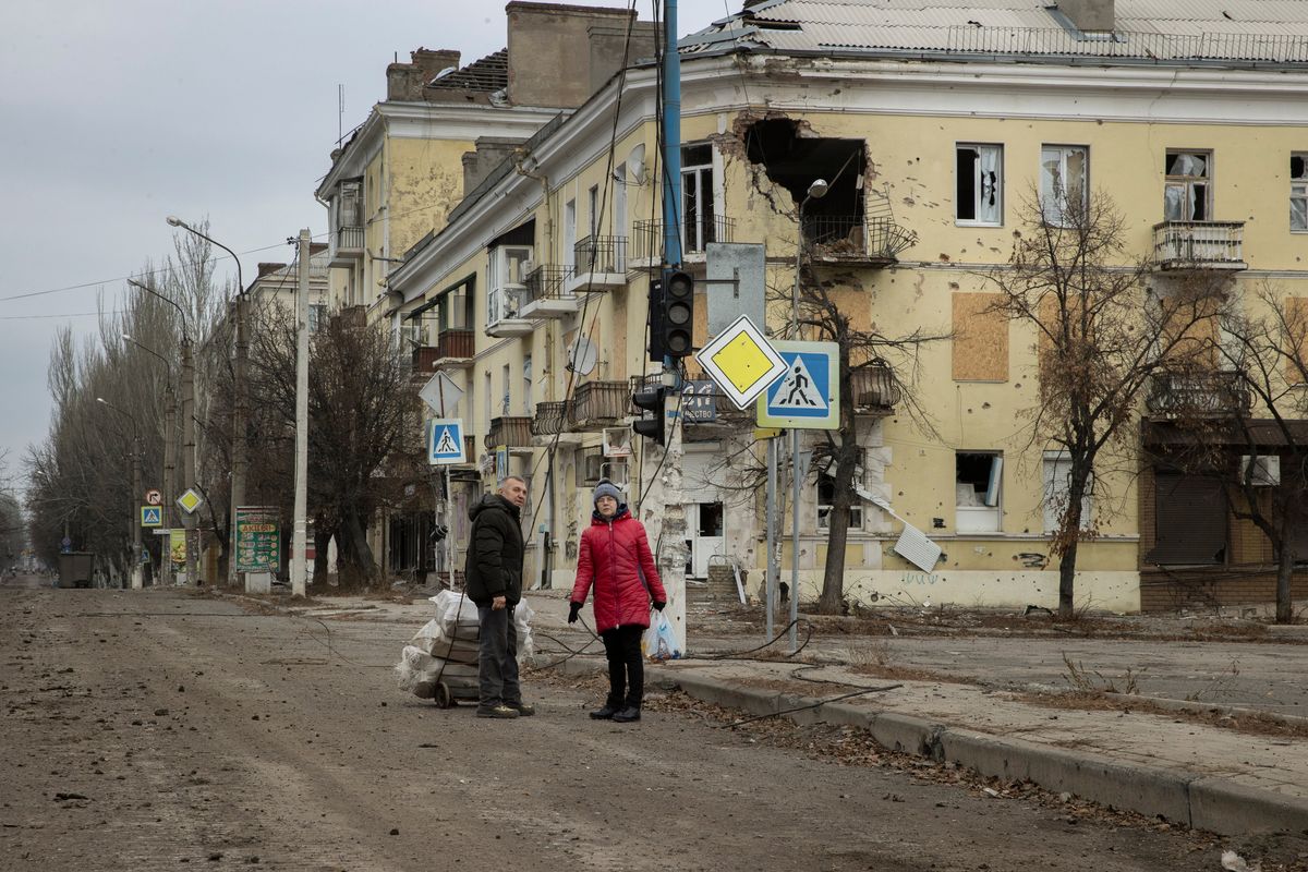 Pedestrians survey battle-damaged buildings in Bakhmut, a frontline city that continues to weather Russian attacks, in the Donbas region of Ukraine on Dec. 24, 2022. There is no electricity or running water in Bakhmut, which makes life for remaining residents increasingly difficult as temperatures drop. (Tyler Hicks/The New York Times)  (TYLER HICKS)