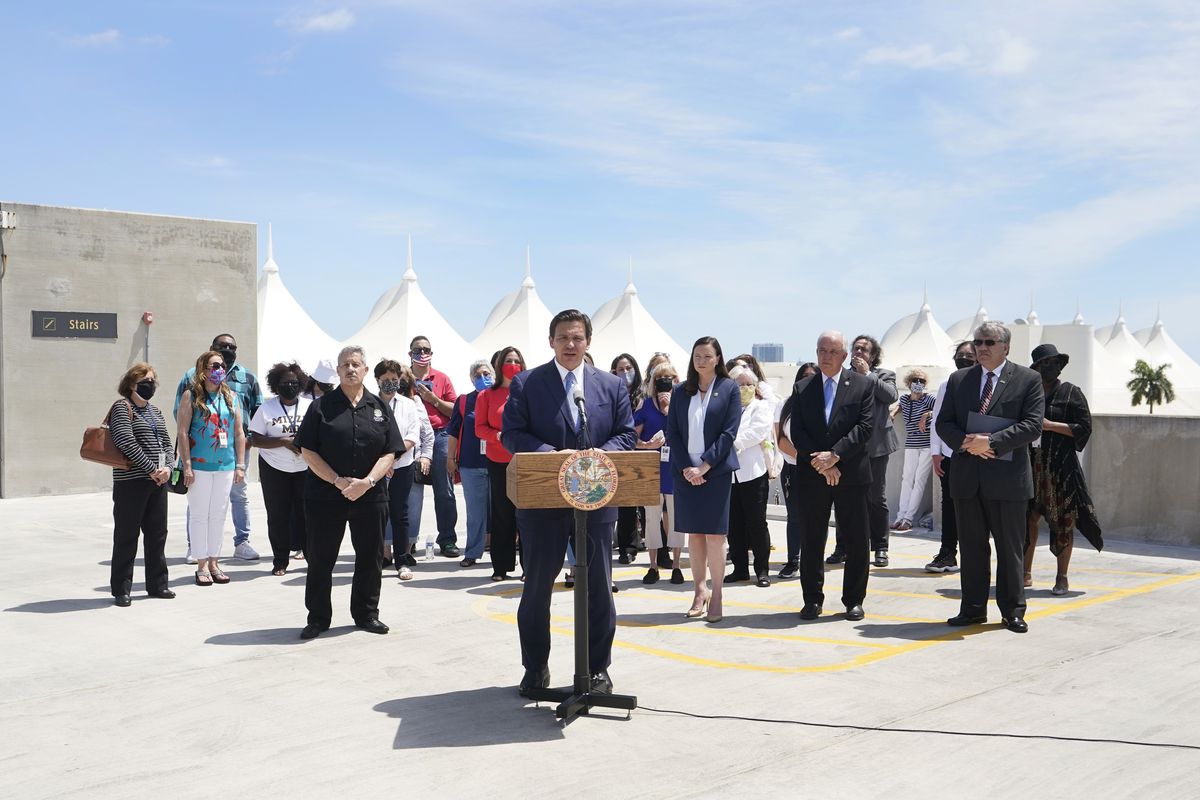 Florida Gov. Ron DeSantis, center, speaks during a news conference surrounded by cruise workers, Thursday, April 8, 2021, at PortMiami in Miami. DeSantis announced a lawsuit against the federal government and the CDC demanding that cruise ships be allowed to sail.  (Wilfredo Lee/Associated Press)