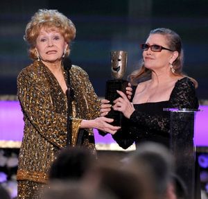 In this Jan. 25, 2015, file photo, Carrie Fisher, right, presents her mother Debbie Reynolds with the Screen Actors Guild life achievement award at the 21st annual Screen Actors Guild Awards at the Shrine Auditorium in Los Angeles. "La La Land" star Ryan Gosling thanked Reynolds at the Palm Springs Film Festival on Monday, Jan. 2, 2017, for serving as an inspiration to the cast and crew of the film. (Photo by Vince Bucci/Invision/AP, File) 