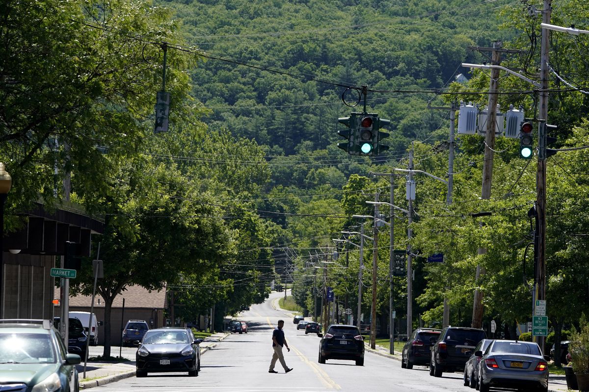 A man walks across the street in Ellenville, N.Y., Wednesday, June 16, 2021. Less than 100 miles north of New York City, Ulster County is popular destination for weekenders headed to Woodstock or the Catskill Mountains. Though pretty, there are pockets of poverty. The county is working with the Center for Guaranteed Income Research at the University of Pennsylvania on a pilot program funded by private donations. One hundred households making less than $46,900 a year in May began receiving a $500 payment each month for a year. Recipients of the money can spend it as they wish, but will be asked to participate in periodic surveys about their physical health, mental health and employment status.  (Seth Wenig)